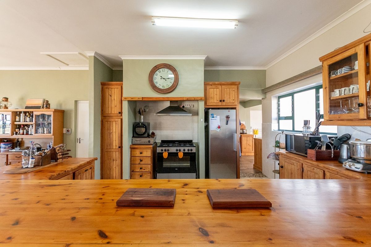 A spacious kitchen featuring extensive wooden cabinetry, a gas stove with extractor fan, and large wooden countertops, offering a warm and functional cooking space.