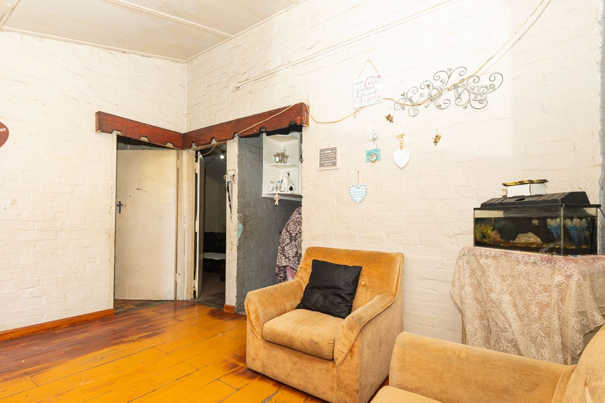 Living area featuring exposed brick walls and original timber flooring, requiring cosmetic updates to enhance the interior aesthetic.