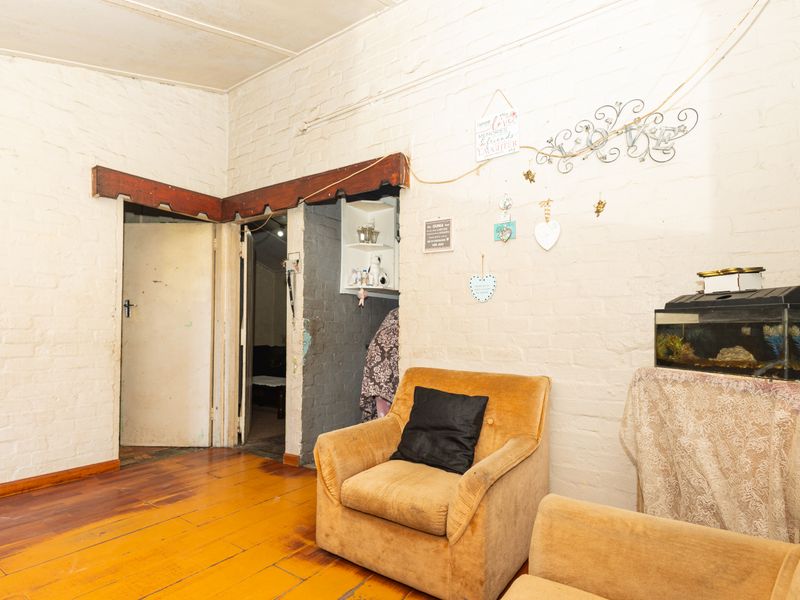 Living area featuring exposed brick walls and original timber flooring, requiring cosmetic updates to enhance the interior aesthetic.