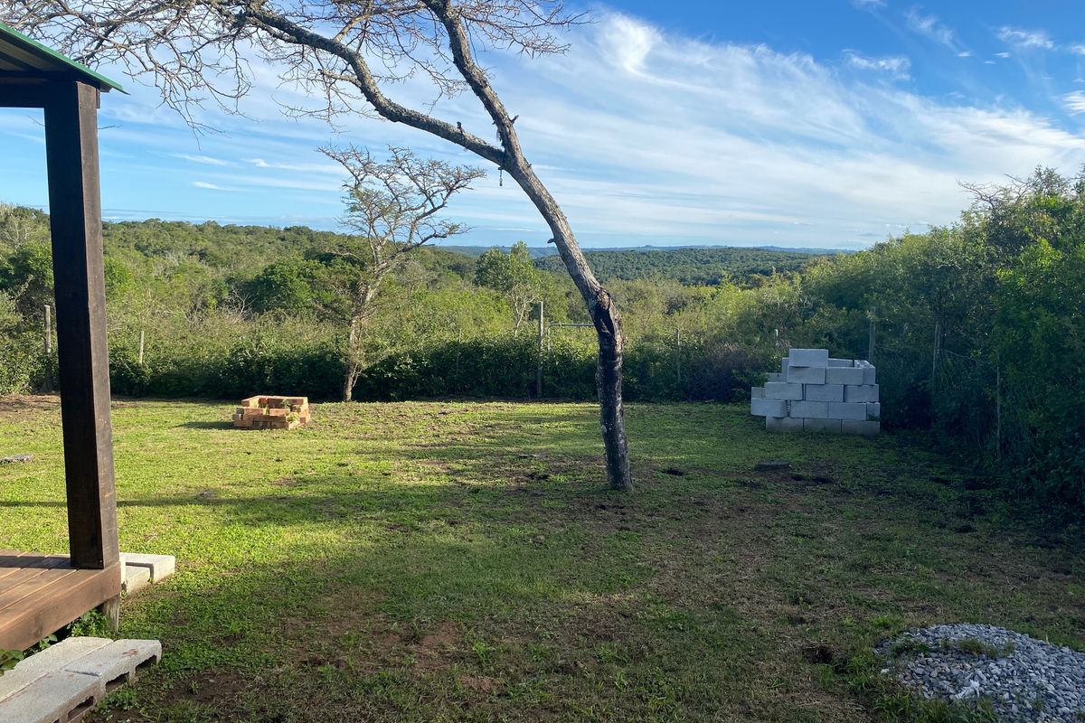 A spacious residential garden area featuring a wooden deck, natural landscaping, and scenic views of the surrounding bushveld.