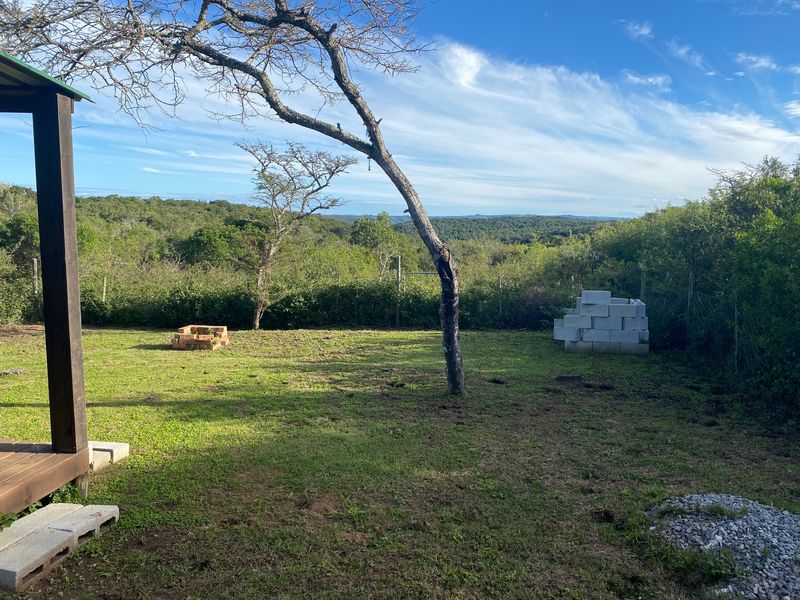 A spacious residential garden area featuring a wooden deck, natural landscaping, and scenic views of the surrounding bushveld.