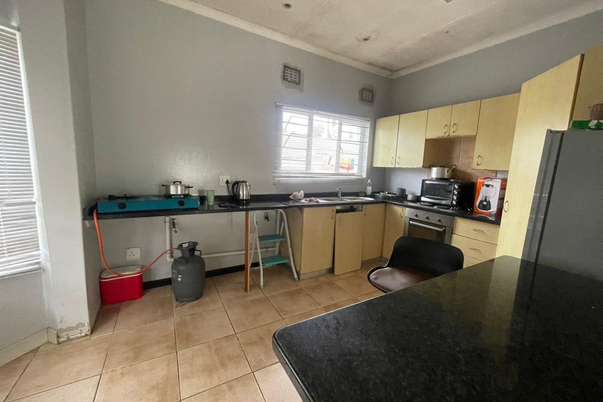 A functional kitchen featuring built-in cabinetry, dark countertops, and tiled flooring, requiring cosmetic updates to modernize the space.
