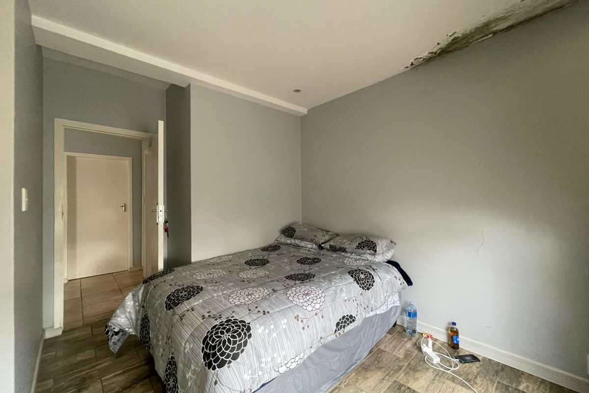 A bedroom featuring tiled flooring and recessed lighting, currently showing significant signs of ceiling water damage and wall cracking requiring repair.