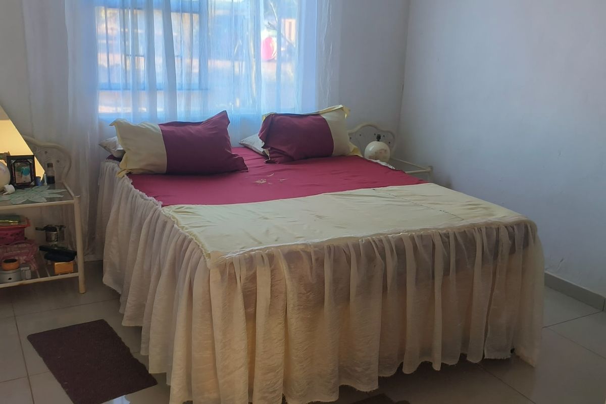 A standard bedroom featuring tiled flooring and natural light through the window, requiring minor cosmetic updates to the walls and door frame.