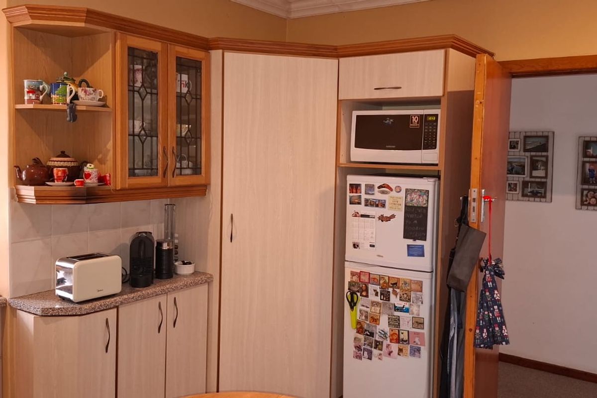 A functional kitchen featuring light-toned cabinetry, laminate countertops, and a built-in microwave unit, offering a practical layout for daily use.