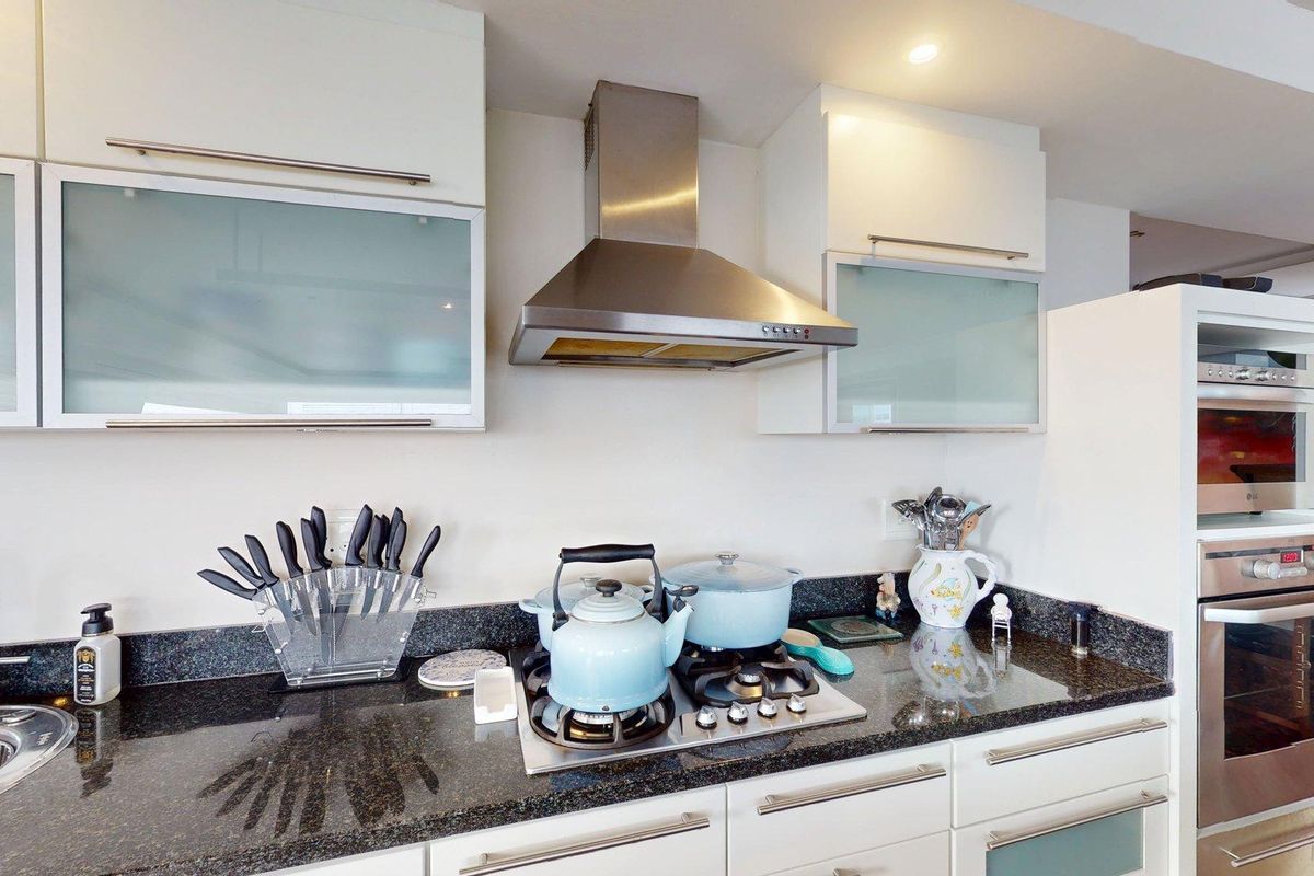 Modern kitchen featuring high-gloss cabinetry, granite countertops, stainless steel gas hob, extractor fan, and integrated built-in oven and microwave appliances.