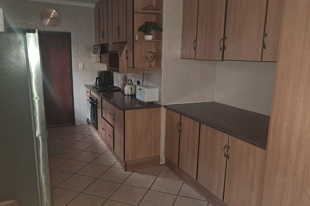 A functional kitchen featuring laminate cabinetry, dark countertops, tiled flooring, and built-in cooking appliances, offering a practical layout for daily meal preparation.