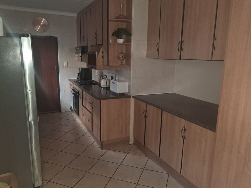 A functional kitchen featuring laminate cabinetry, dark countertops, tiled flooring, and built-in cooking appliances, offering a practical layout for daily meal preparation.