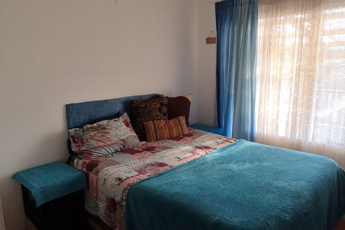 A standard bedroom featuring a window with layered curtains, providing natural light and a simple, functional layout.