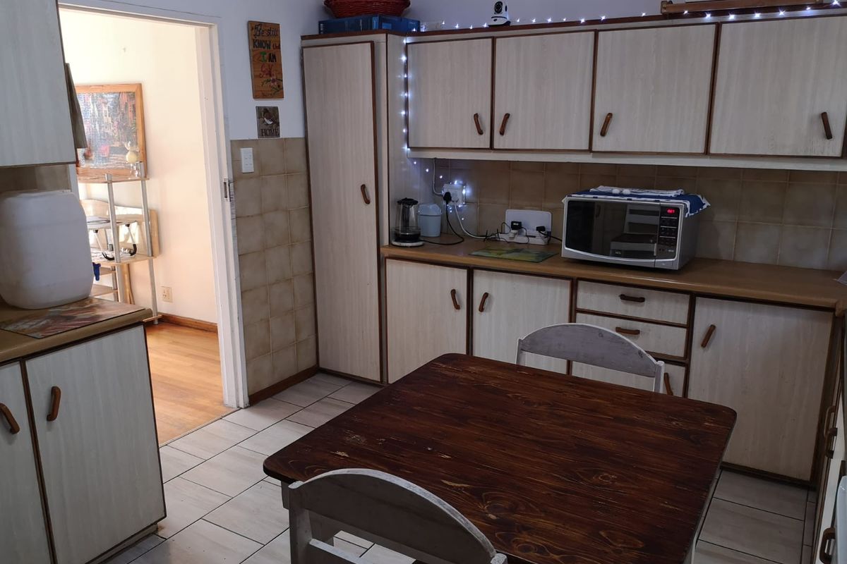 A functional kitchen featuring laminate cabinetry, tiled backsplash, and tiled flooring, offering a practical layout with ample storage space.