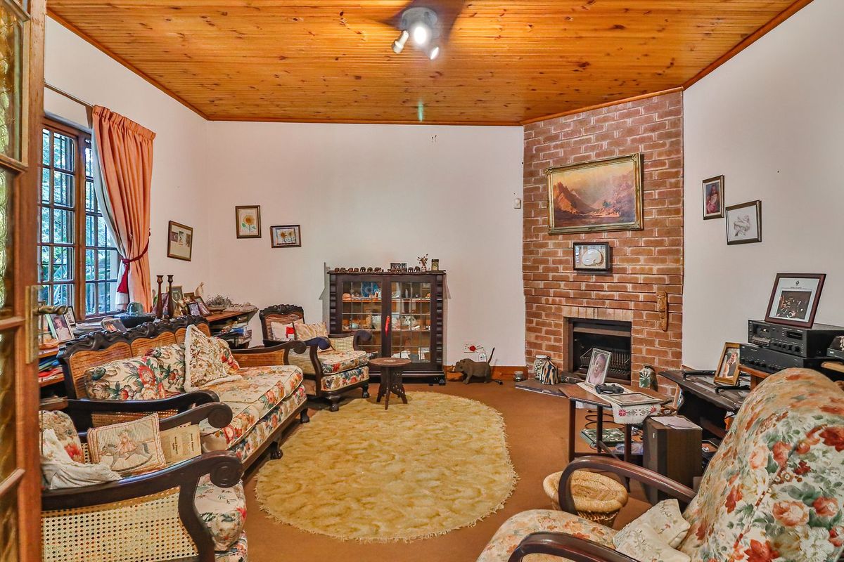 A cozy living room featuring a classic brick fireplace and a warm timber-paneled ceiling, offering a traditional and inviting atmosphere.