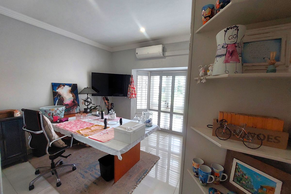 A living area featuring tiled flooring, built-in shelving, and shutter blinds, equipped with a split-system air conditioner for climate control.