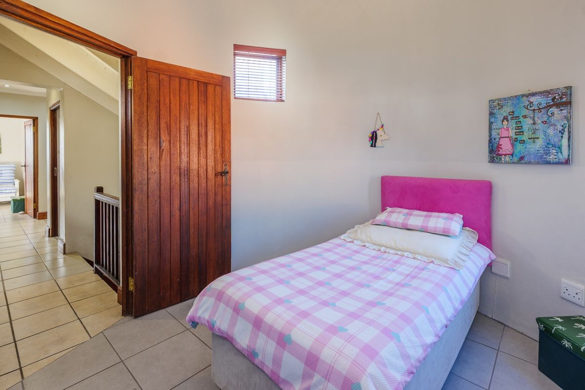 A bedroom featuring tiled flooring, a solid timber door, and natural light through venetian blinds, providing a functional and well-maintained living space.