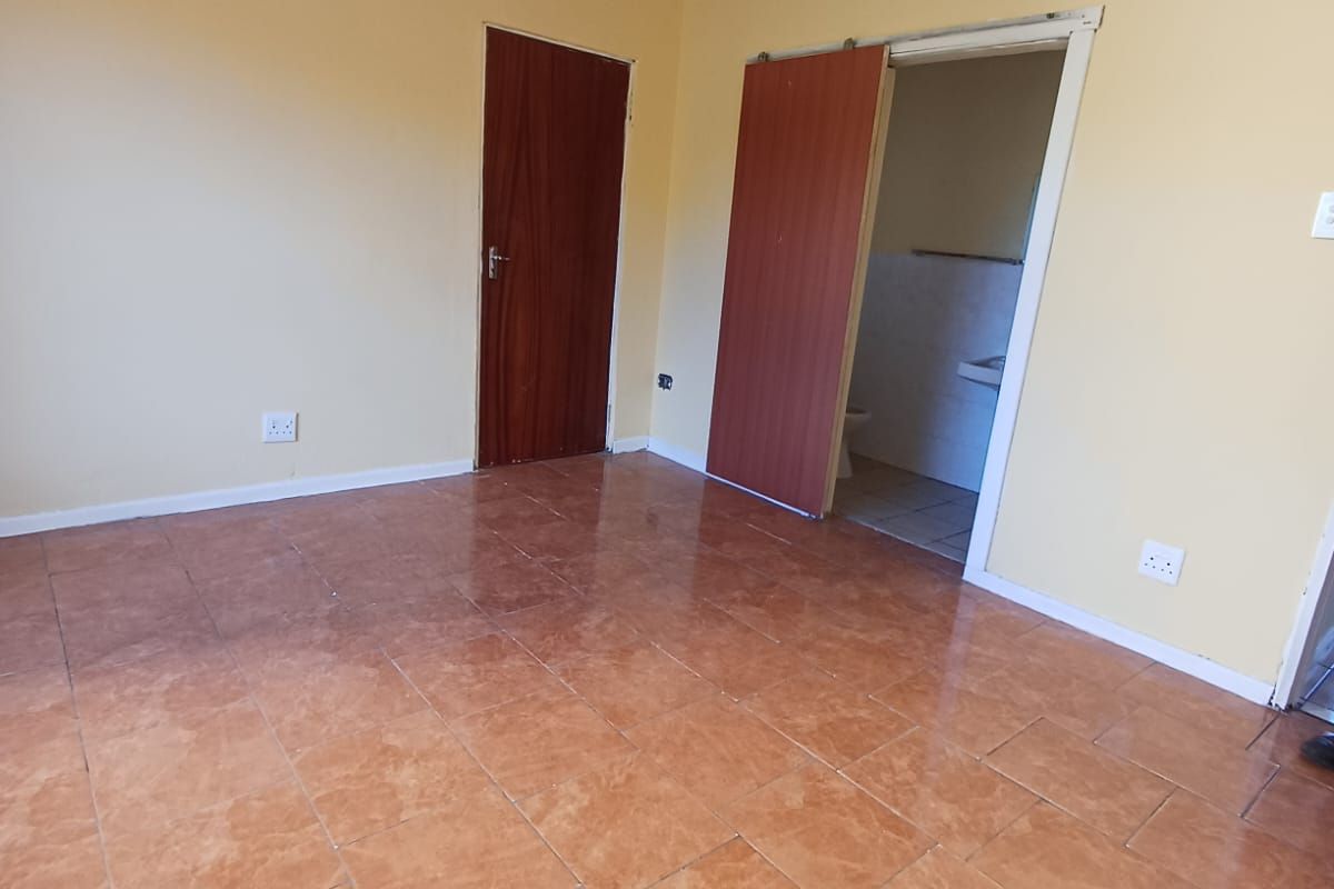 An empty bedroom featuring tiled flooring and direct access to an en-suite bathroom, providing a blank canvas for renovation or staging.