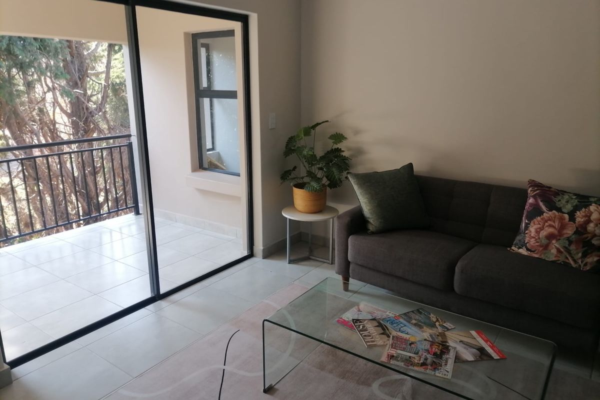 A bright living room featuring large sliding glass doors that open onto a private balcony, providing natural light and seamless indoor-outdoor flow.
