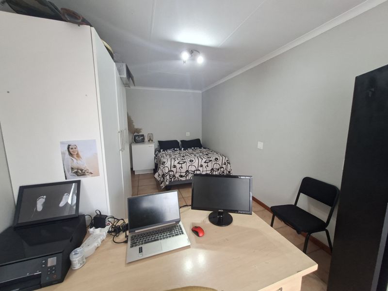 A functional bedroom featuring tiled flooring and neutral wall finishes, providing a versatile space for rest or study.