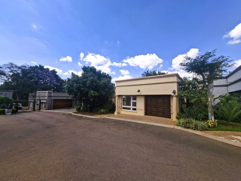 Front exterior view of the property featuring a paved driveway, garage access, and established garden landscaping.