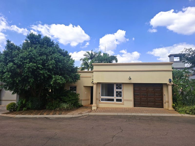 Front elevation of a residential property featuring a single garage, paved driveway, and decorative architectural columns.