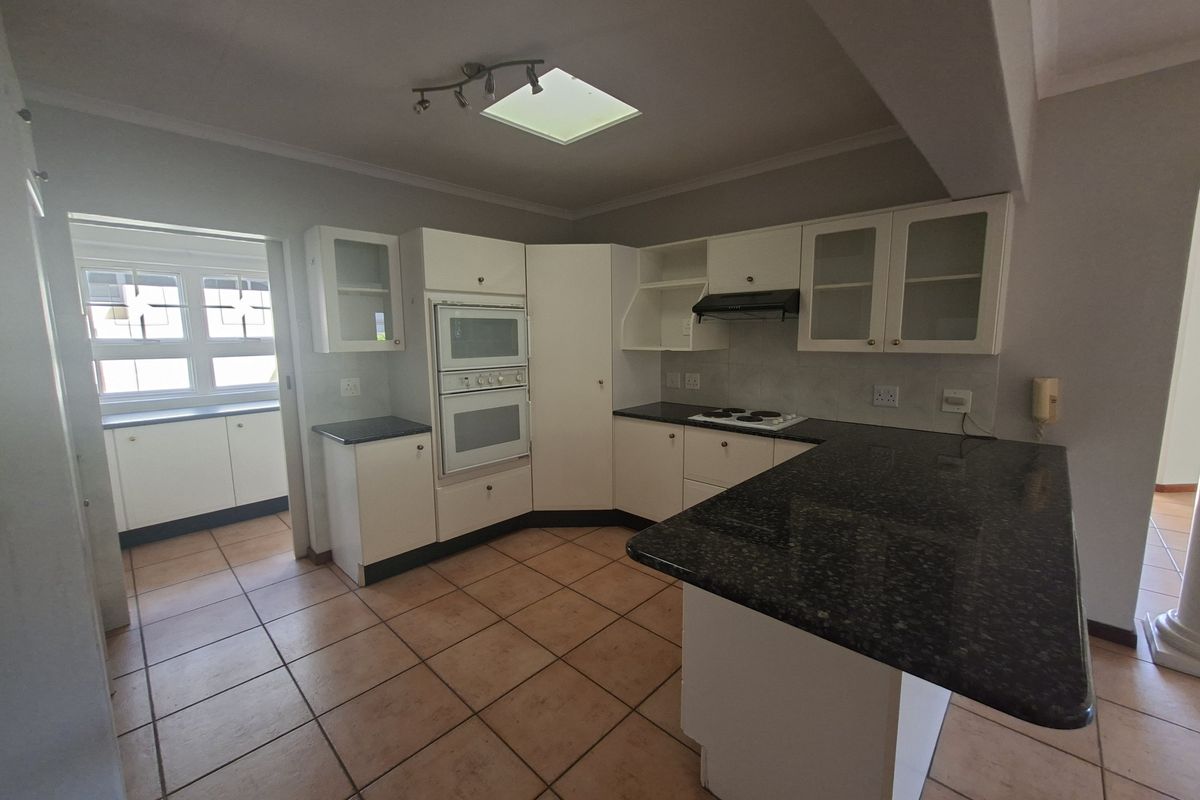 A functional kitchen featuring granite countertops, built-in oven, electric hob, and a skylight, offering a clean layout ready for modern updates.