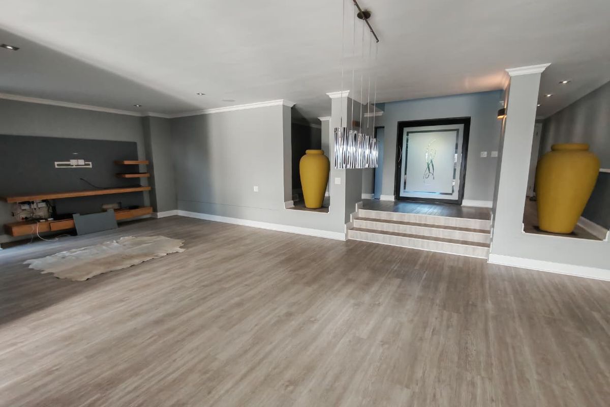 Spacious living area featuring light wood-look flooring, a built-in media console, recessed display niches, and a raised entrance foyer with decorative glass door.