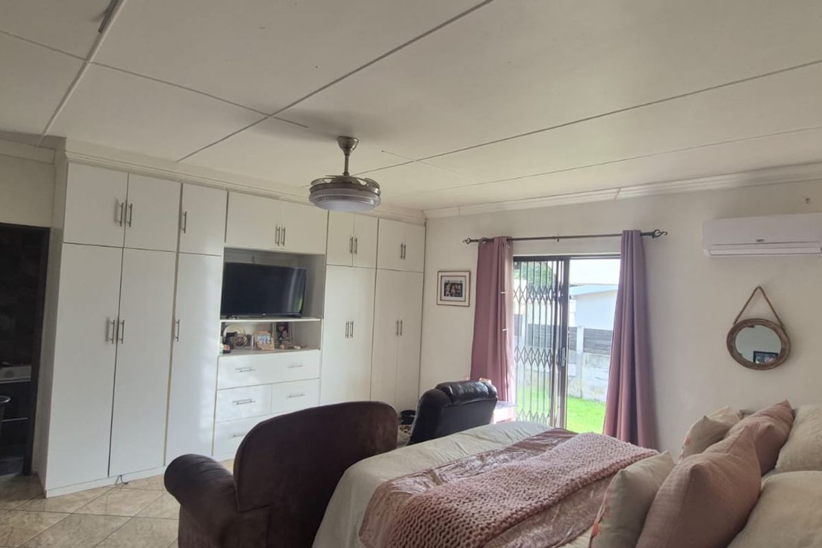 Spacious bedroom featuring extensive built-in cabinetry, tiled flooring, a ceiling fan, and a split-system air conditioner with direct access to the exterior.