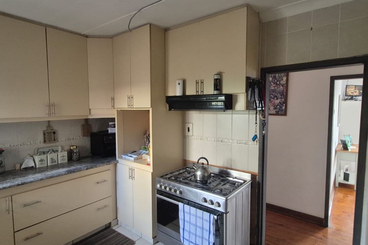 Functional kitchen featuring built-in cabinetry, laminate countertops, a gas stove with extractor fan, and tiled backsplash, offering potential for modern updates.