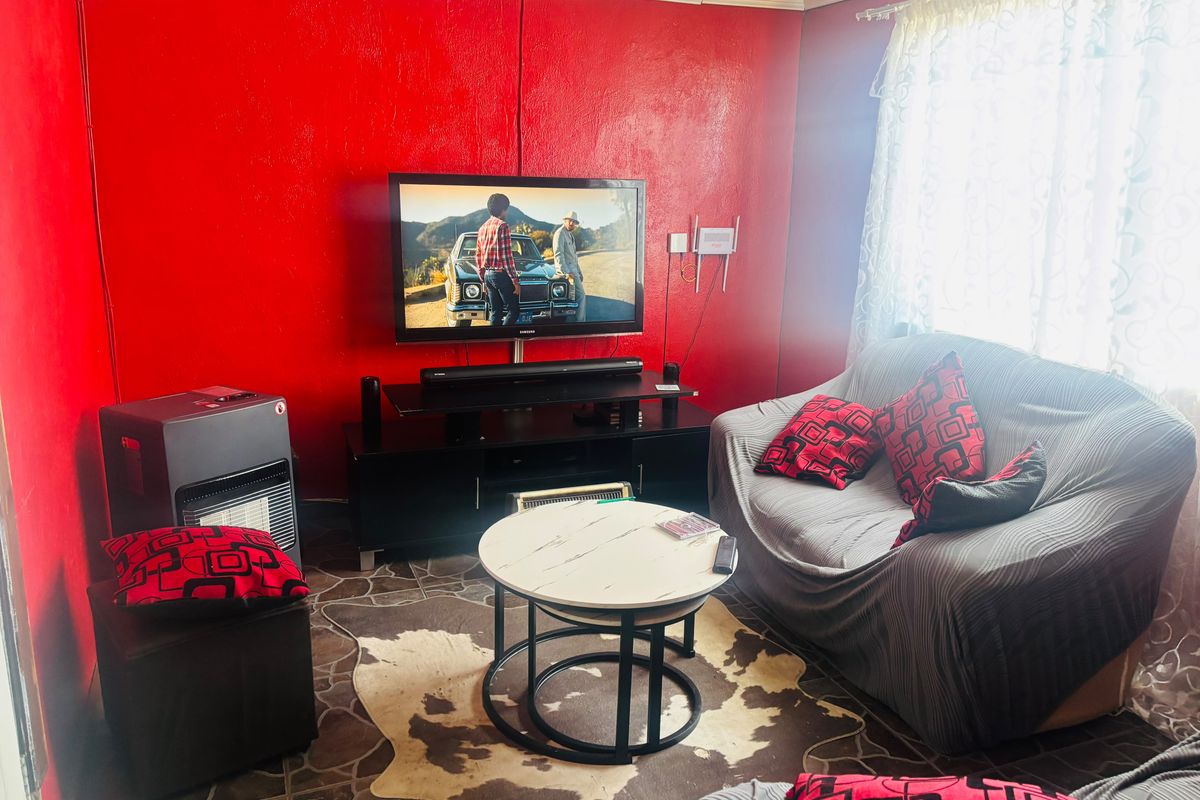 A living room featuring bold red walls, tiled flooring, and a wall-mounted television setup.