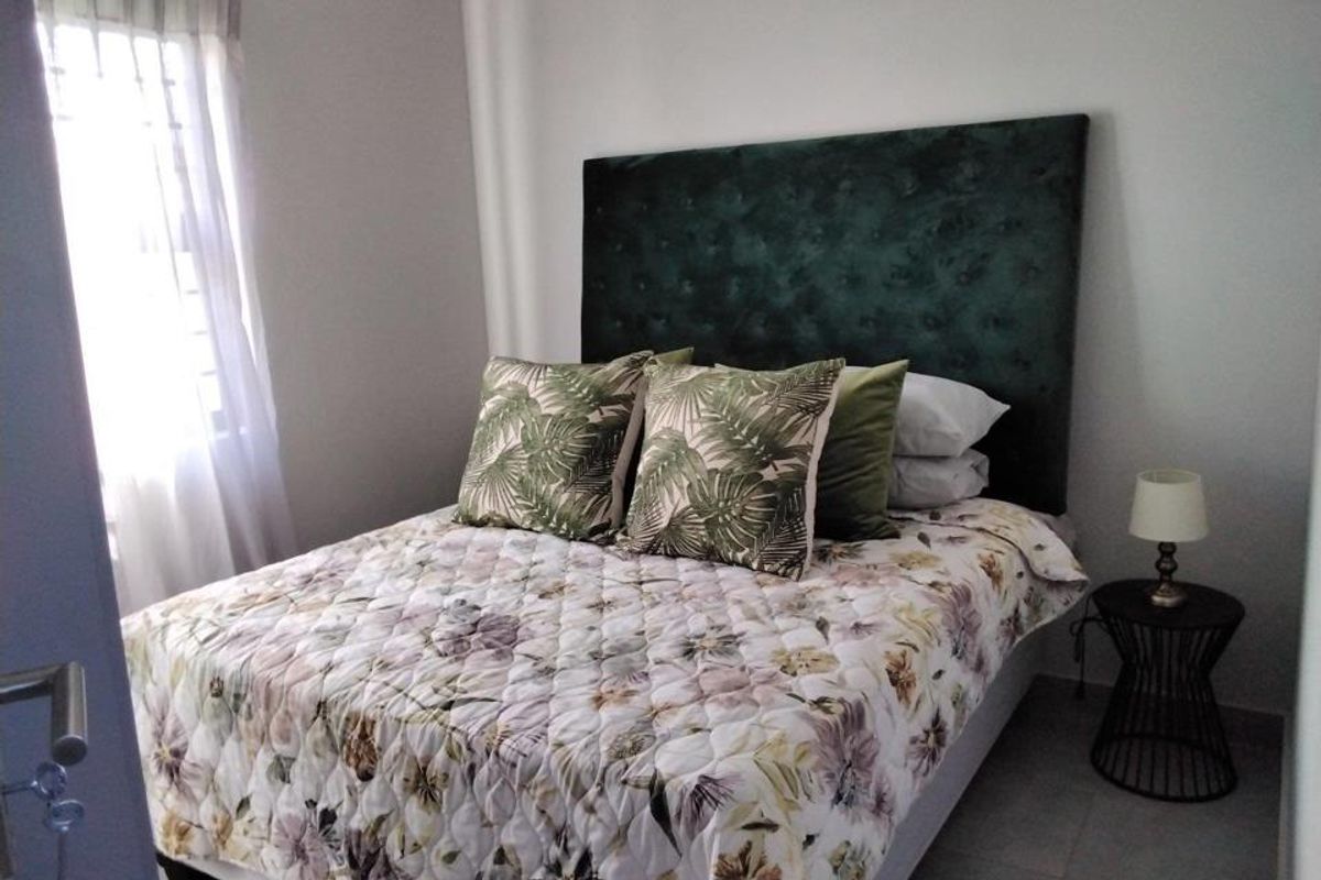A well-maintained bedroom featuring neutral wall finishes, tiled flooring, and a window with fitted curtain tracks.