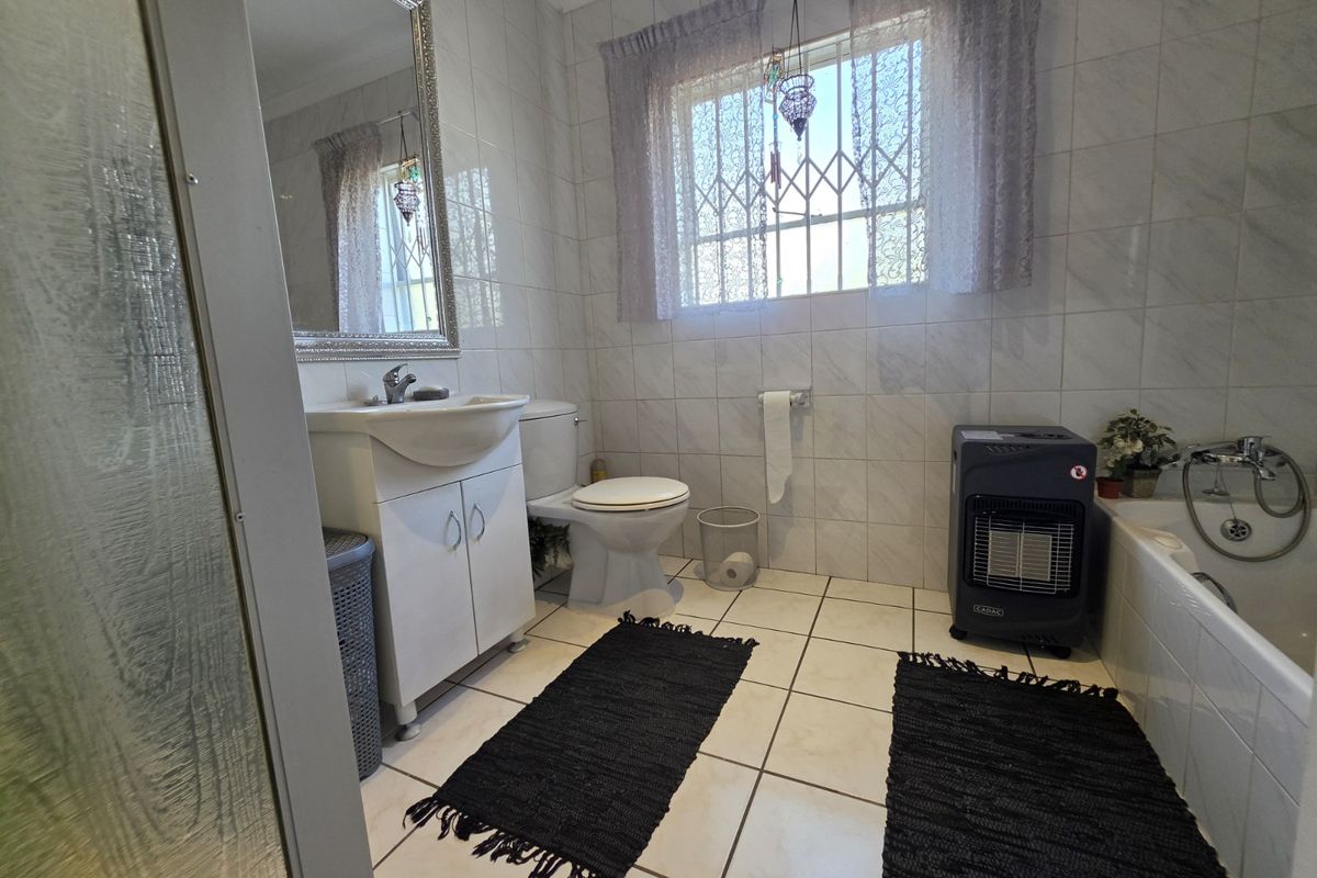 A functional bathroom featuring a vanity cabinet, toilet, bathtub, and shower enclosure with tiled walls and floors.