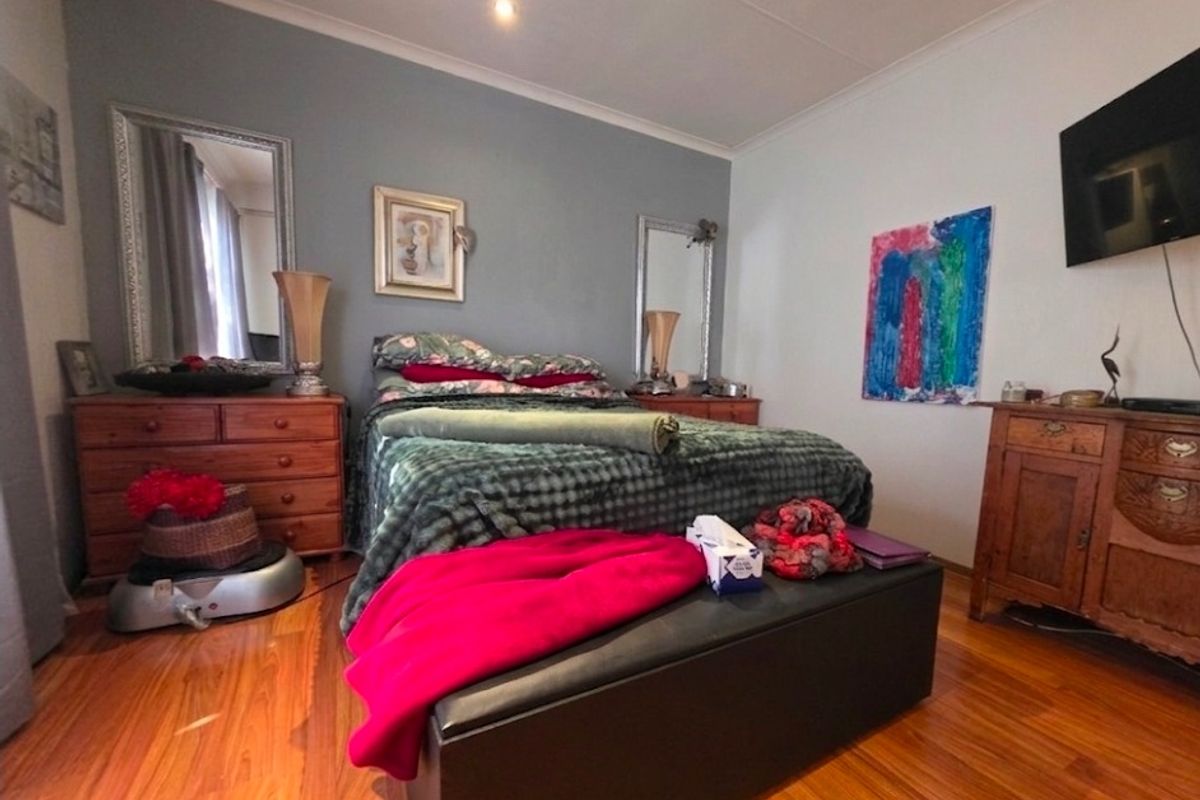 A bedroom featuring laminate timber flooring and recessed downlighting, providing a functional space with neutral wall tones.