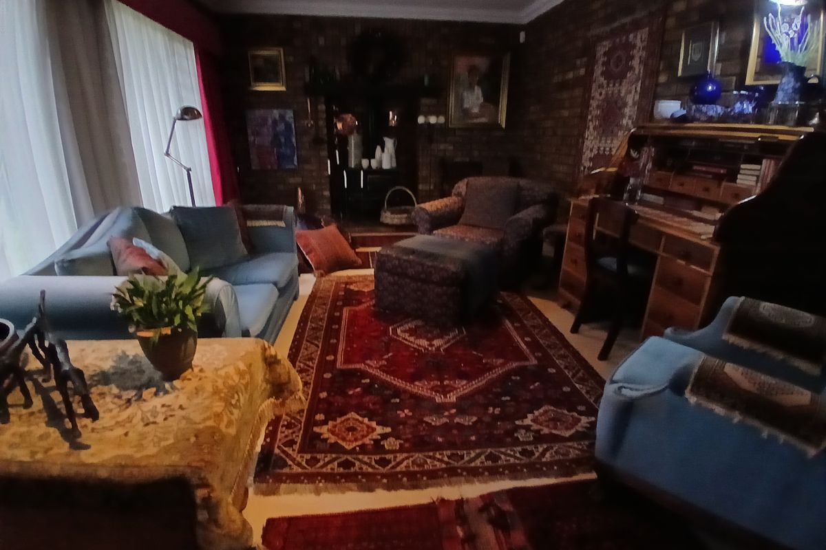 A living room featuring exposed brick walls and large windows, providing a traditional aesthetic with potential for modern updates.