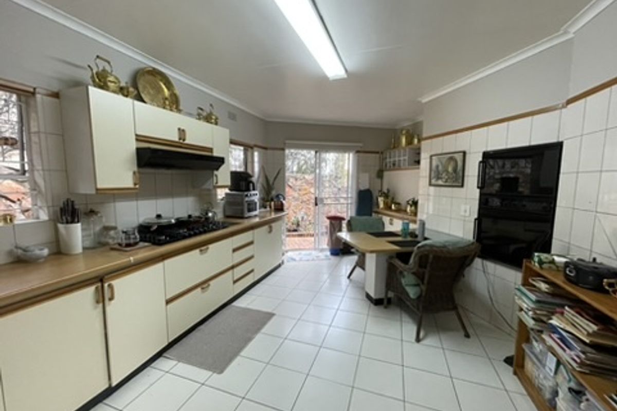 A functional kitchen featuring built-in cabinetry, a gas hob, an integrated oven, and tiled flooring with direct access to the outdoor area.