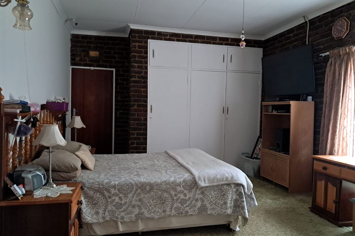 A bedroom featuring exposed brick walls, built-in cupboards, and carpeted flooring, offering a dated aesthetic with potential for modernization.