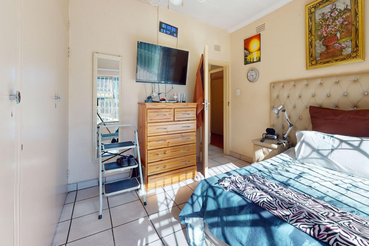A functional bedroom featuring tiled flooring and built-in cupboard storage, offering a practical layout with natural light.