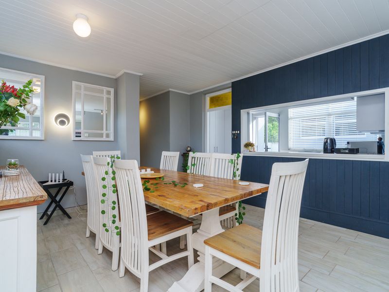 A well-lit dining room featuring tiled flooring, a tongue and groove ceiling, and a convenient pass-through window connecting to the kitchen area.