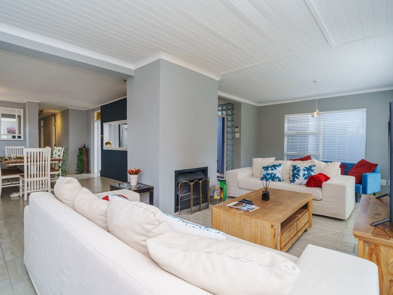 Spacious open-plan living and dining area featuring a central fireplace, tongue and groove ceiling, and neutral tiled flooring throughout.