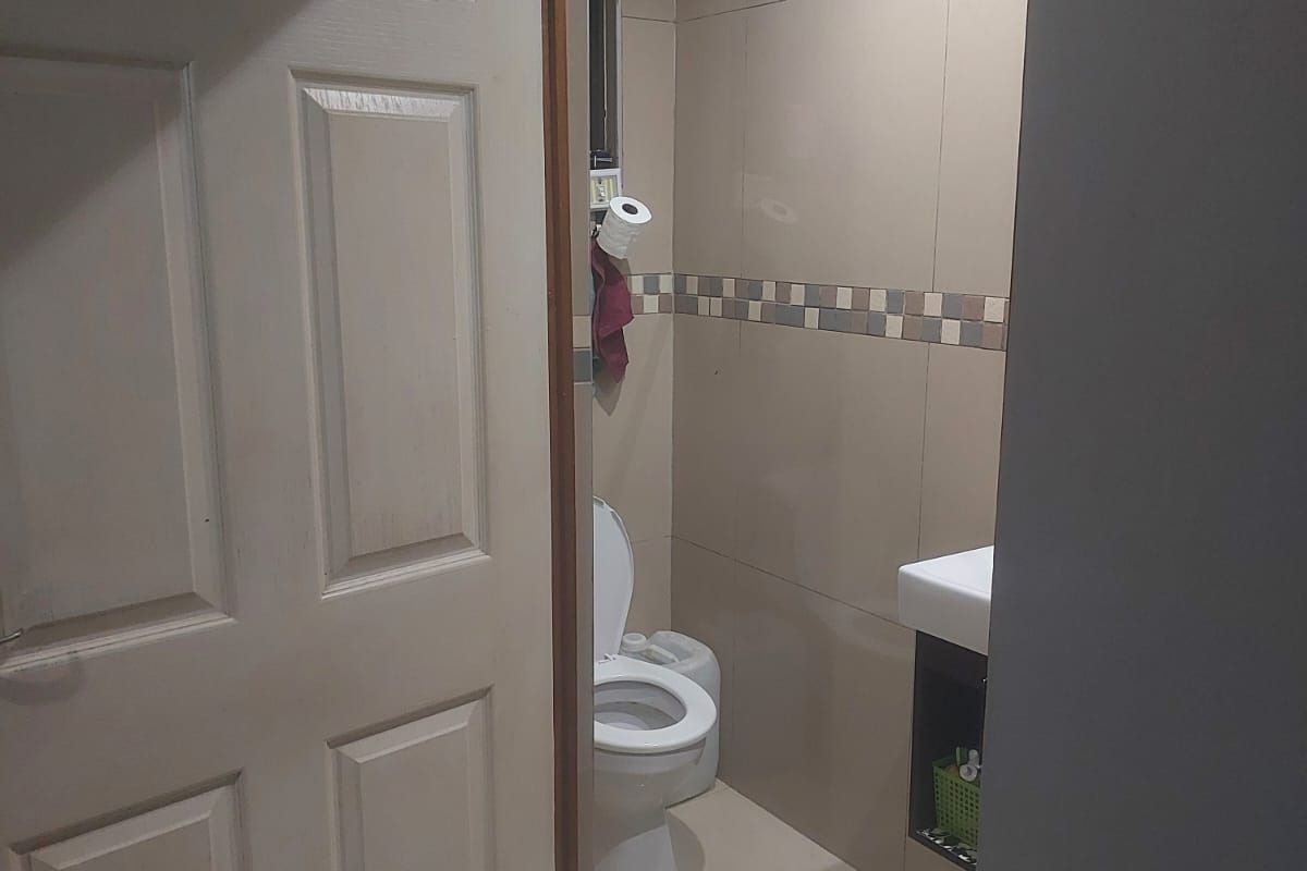A compact bathroom featuring tiled walls, a wall-mounted vanity basin, and a standard toilet suite.