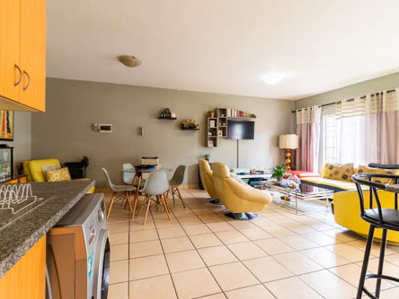 Spacious open-plan living area featuring tiled flooring, integrated kitchen cabinetry with granite countertops, and seamless flow to the lounge and dining space.