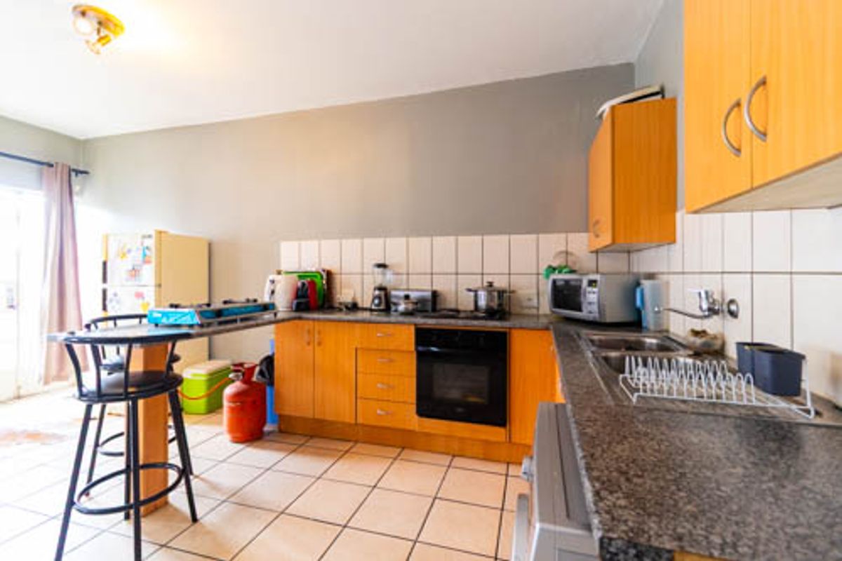 A functional kitchen featuring wooden cabinetry, granite countertops, a built-in oven, and tiled flooring, offering a practical layout for daily meal preparation.