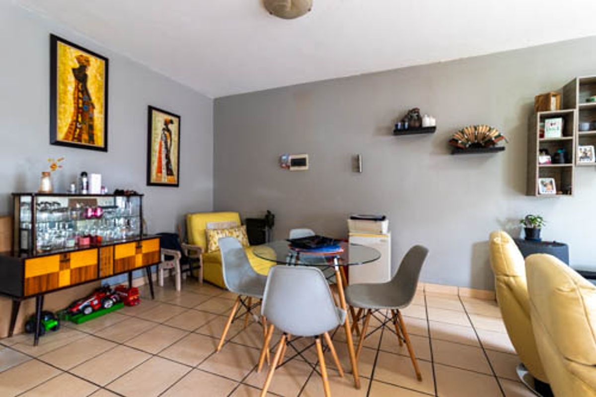 A living area featuring neutral grey walls and tiled flooring, providing a functional space for dining or relaxation.