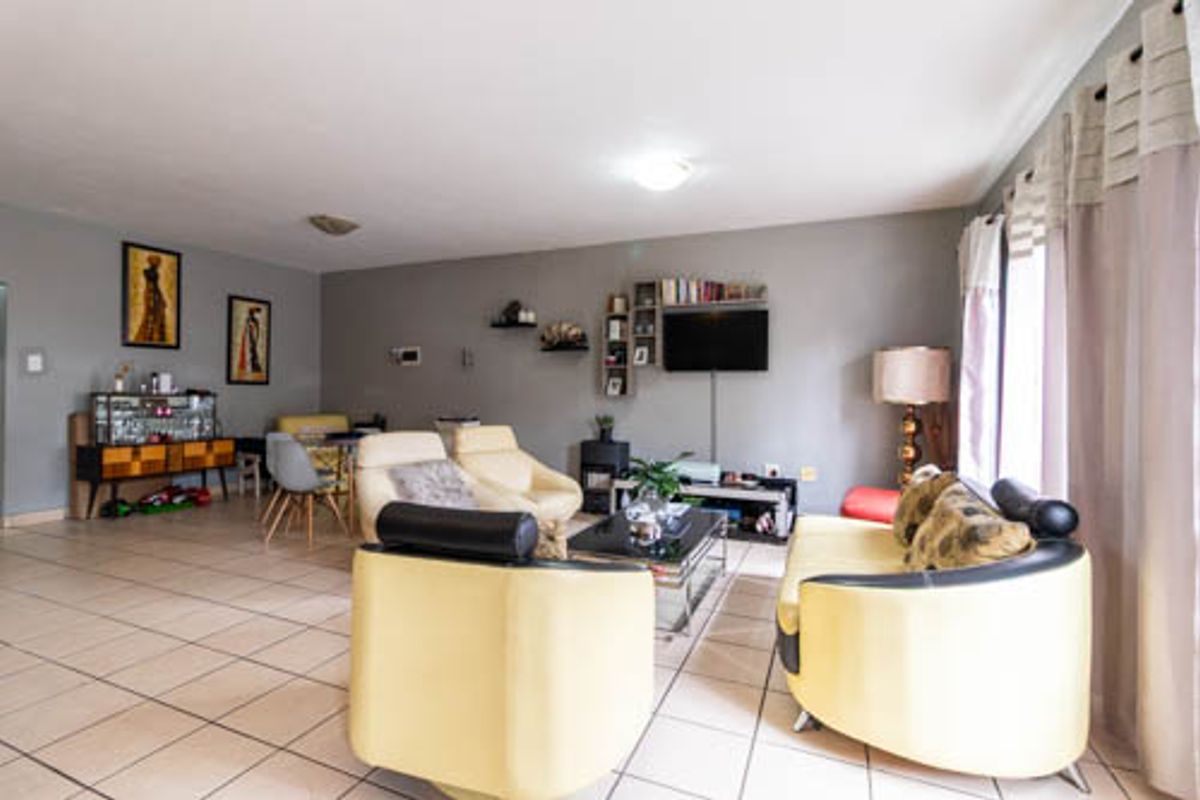 A spacious living room featuring neutral grey walls and ceramic floor tiles, providing a functional and open layout for relaxation and entertainment.
