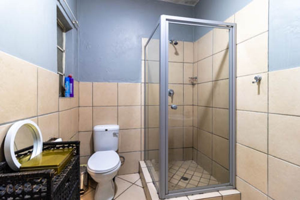 A functional bathroom featuring a glass-enclosed shower, a standard toilet, and neutral wall and floor tiling.