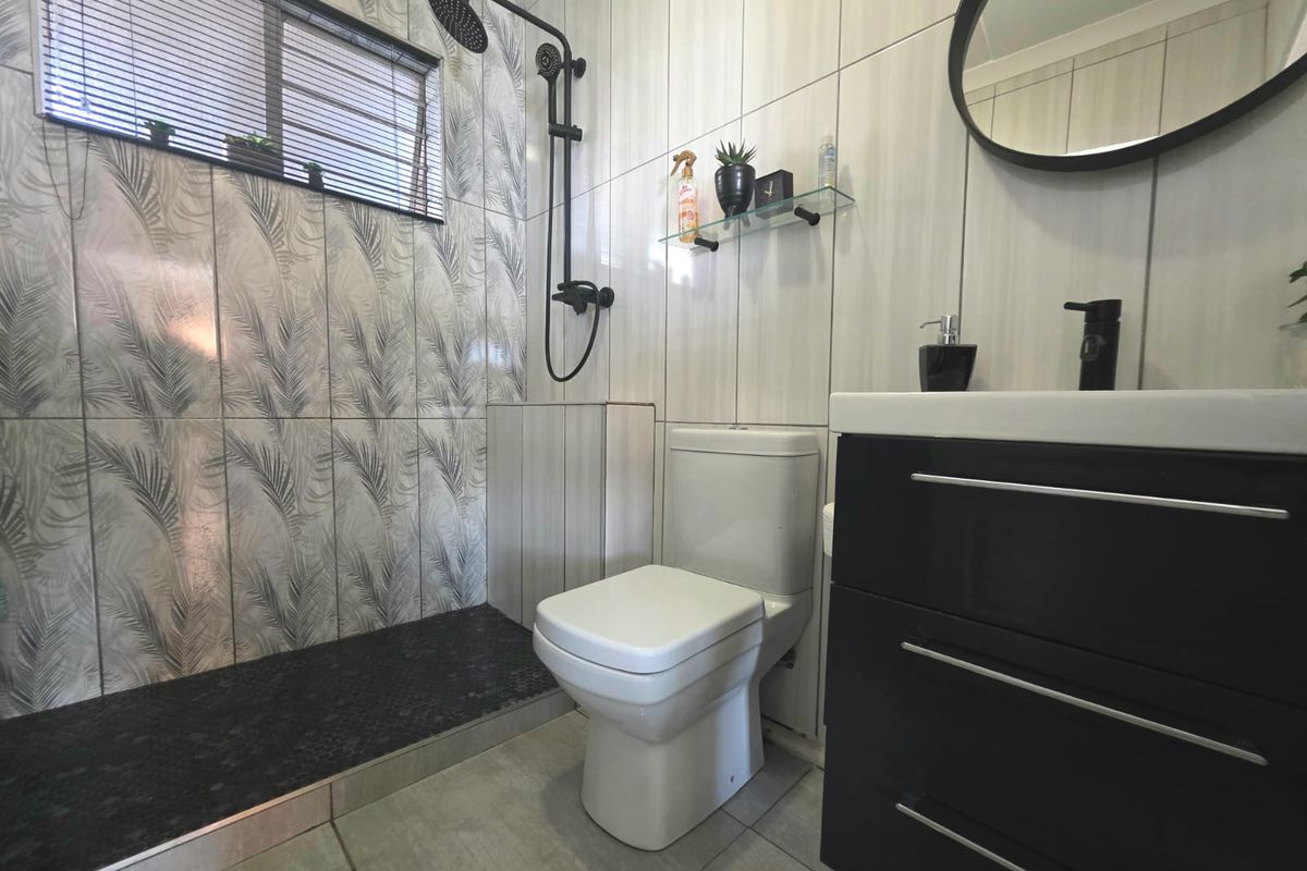 Modern bathroom featuring a walk-in shower with black fixtures, a contemporary vanity unit, and stylish patterned wall tiling.