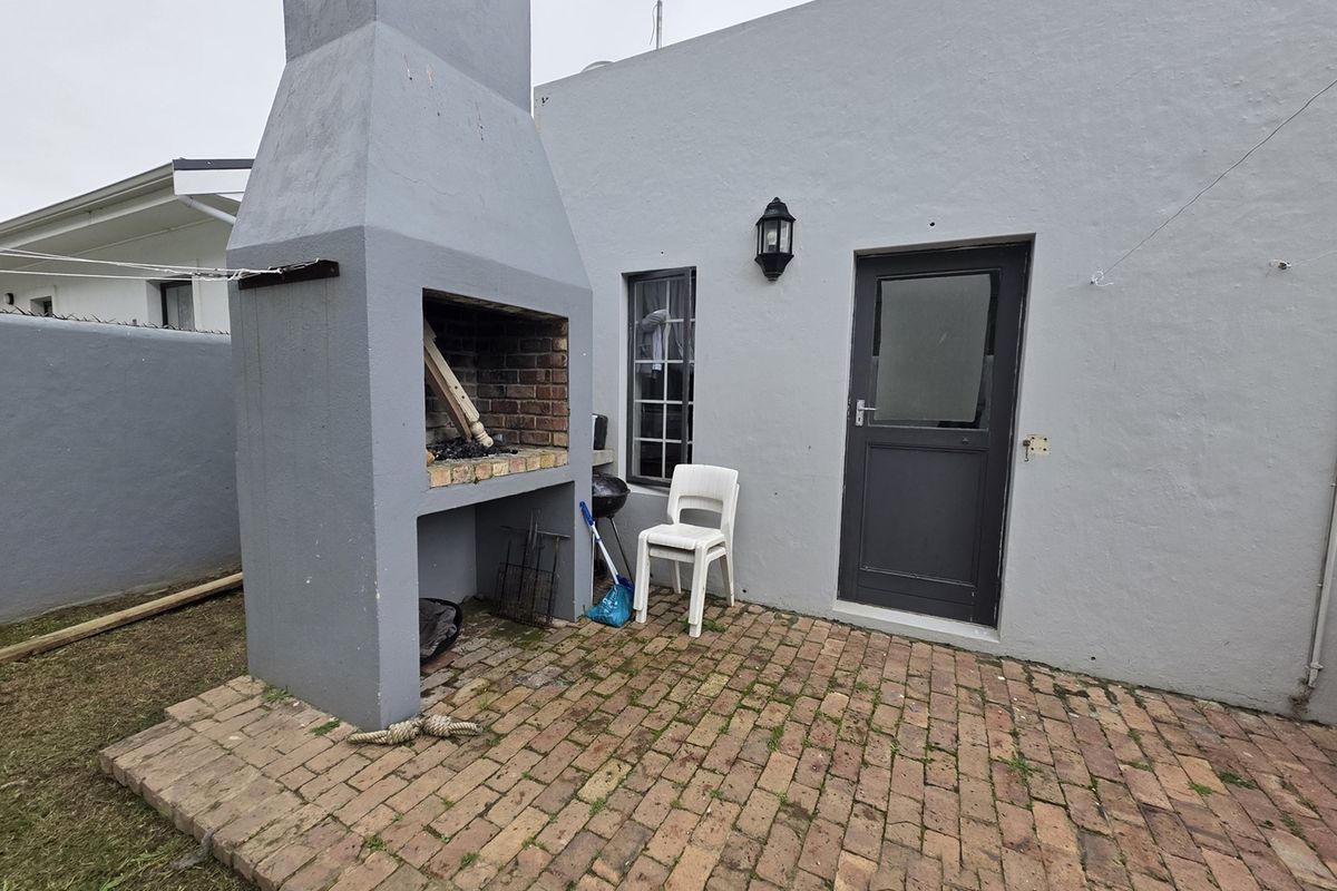 Rear exterior area featuring a built-in brick braai, paved patio space, and direct access to the home via a single door.