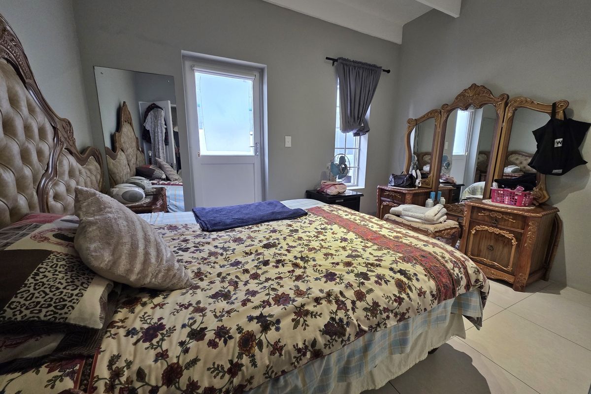A bedroom featuring tiled flooring, exposed ceiling beams, and direct access to an external area through a private door.
