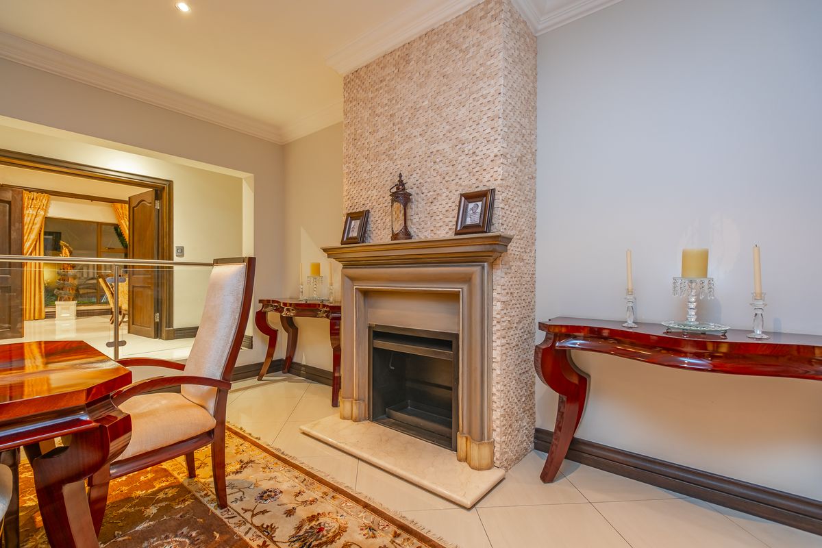 A well-maintained living area featuring a central fireplace with decorative stone cladding, a classic mantelpiece, and polished tiled flooring.