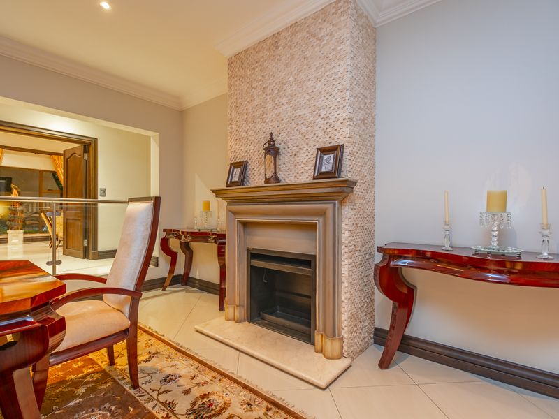 A well-maintained living area featuring a central fireplace with decorative stone cladding, a classic mantelpiece, and polished tiled flooring.