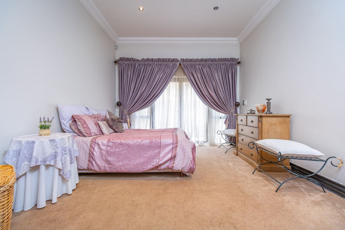 A well-maintained bedroom featuring neutral carpeting, recessed downlighting, decorative cornice, and sliding glass doors providing natural light.