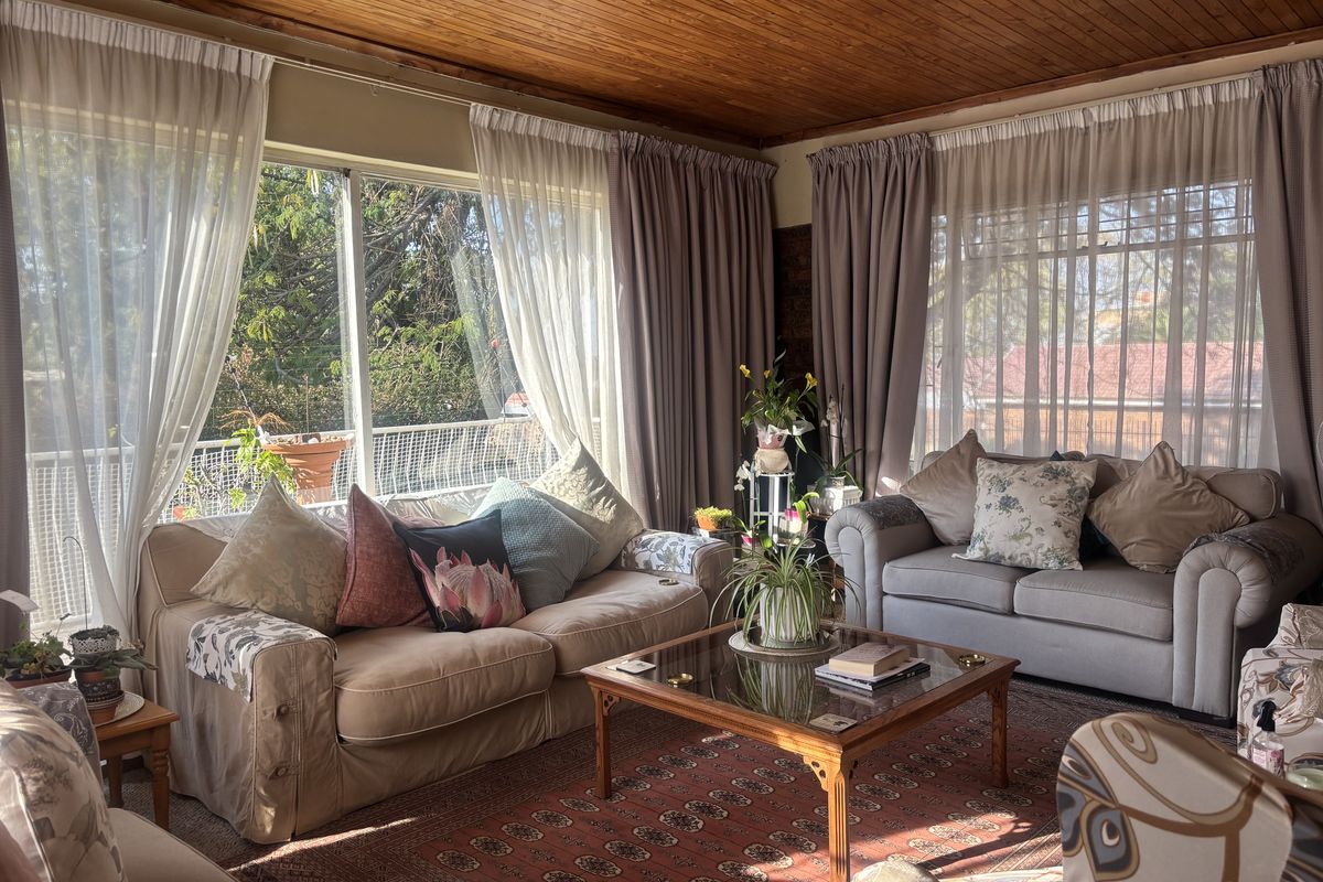 A cozy living room featuring a warm timber-clad ceiling and large windows that provide ample natural light and views of the exterior.