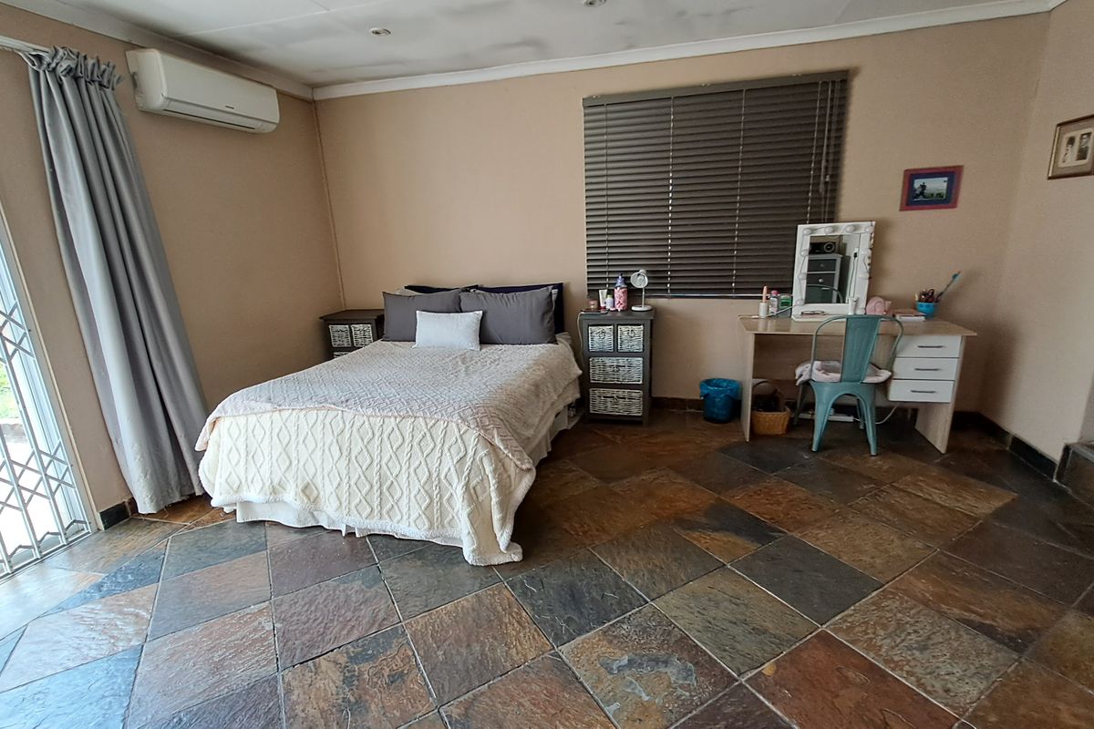 Spacious bedroom featuring durable slate tile flooring, a wall-mounted air conditioning unit, and direct access to the exterior via a security gate.